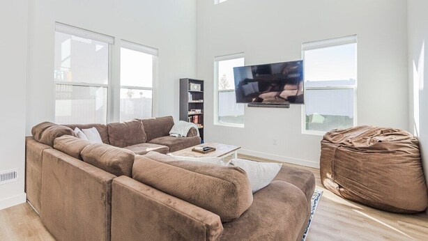 Una sala de estar moderna con un amplio sofá modular, una mesa de centro, un sillón informal y un televisor de pantalla plana montado en la pared.
