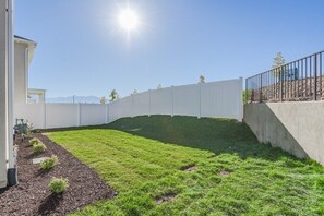 Un patio trasero cercado con césped y un muro de hormigón.