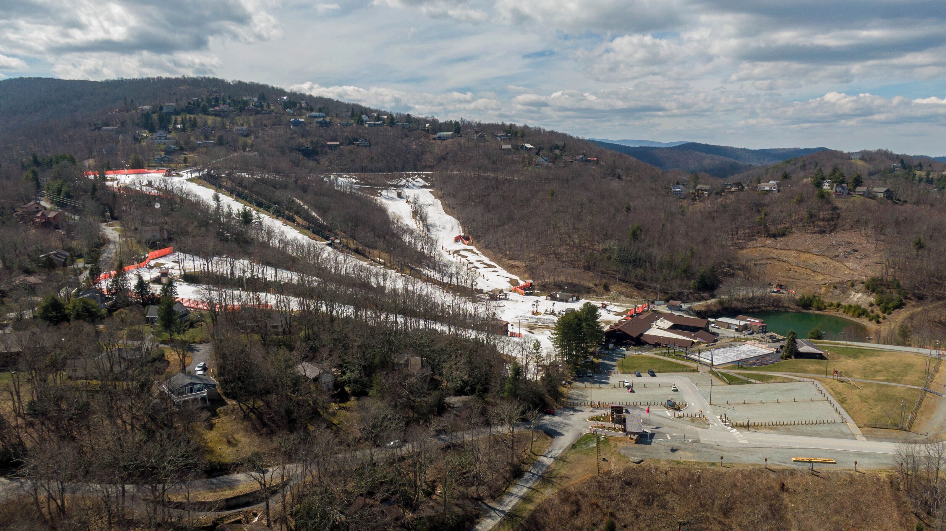 A ski resort with a chairlift, ski slopes, and a parking area.