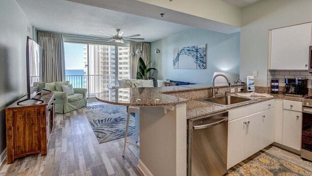 A modern kitchen with granite countertops, stainless steel appliances, and a large island. - Shores of Panama 1118 (Panama City Beach)