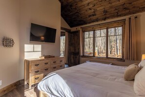 Ein Schlafzimmer mit einem großen Bett, einem hölzernen Schminktisch und einem an der Wand befestigten Fernseher.