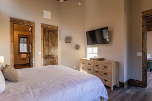 Ein Schlafzimmer mit einem großen Bett, einer Holzkommode und einem flachbildfernseher an der Wand.