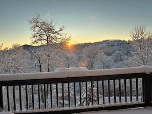 A bench overlooking a snowy landscape with bare trees and a sunset in the background. - Mountain Sunrise (Banner Elk)