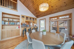 A spacious kitchen with wooden cabinets, a dining table with chairs, and a large window with a view. - Mountain Sunrise (Banner Elk)