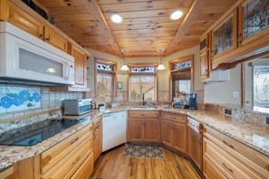A kitchen with wooden cabinets, a microwave, a toaster, and a coffee maker. - Mountain Sunrise (Banner Elk)