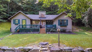 A two-story house with a stone chimney, green shutters, and a front porch with steps leading to a door. - Creek House (Boone)