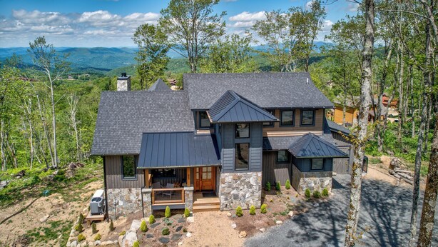 A modern two-story house with a stone foundation, multiple gables, and a large front porch. - Zion at Eagles Nest (Banner Elk)
