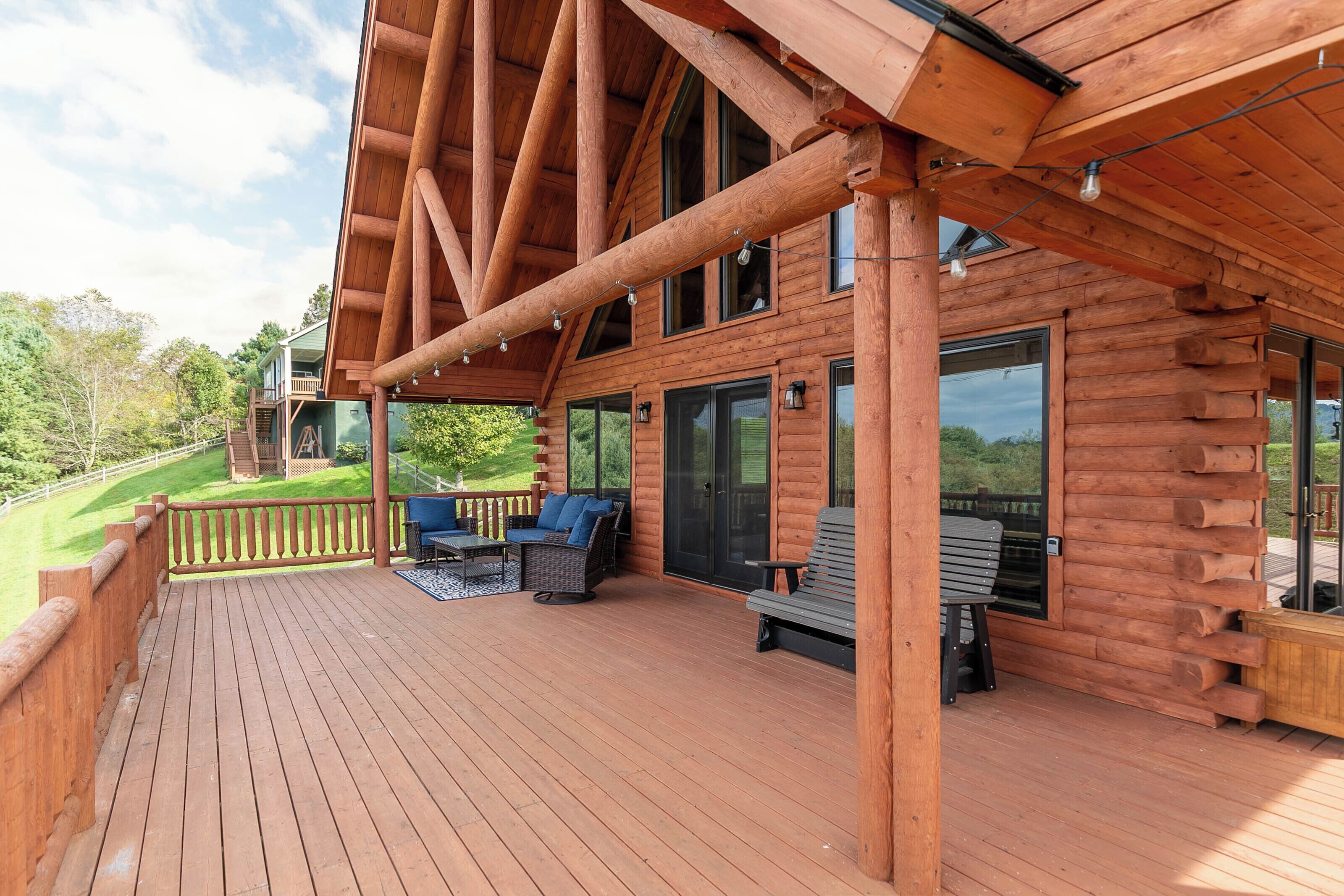 Eine Holzhütte mit einer Veranda, Sitzgelegenheiten im Freien und großen Fenstern.