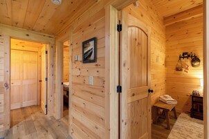 Interior de madera con una puerta, un banco y un cuadro colgado en la pared.