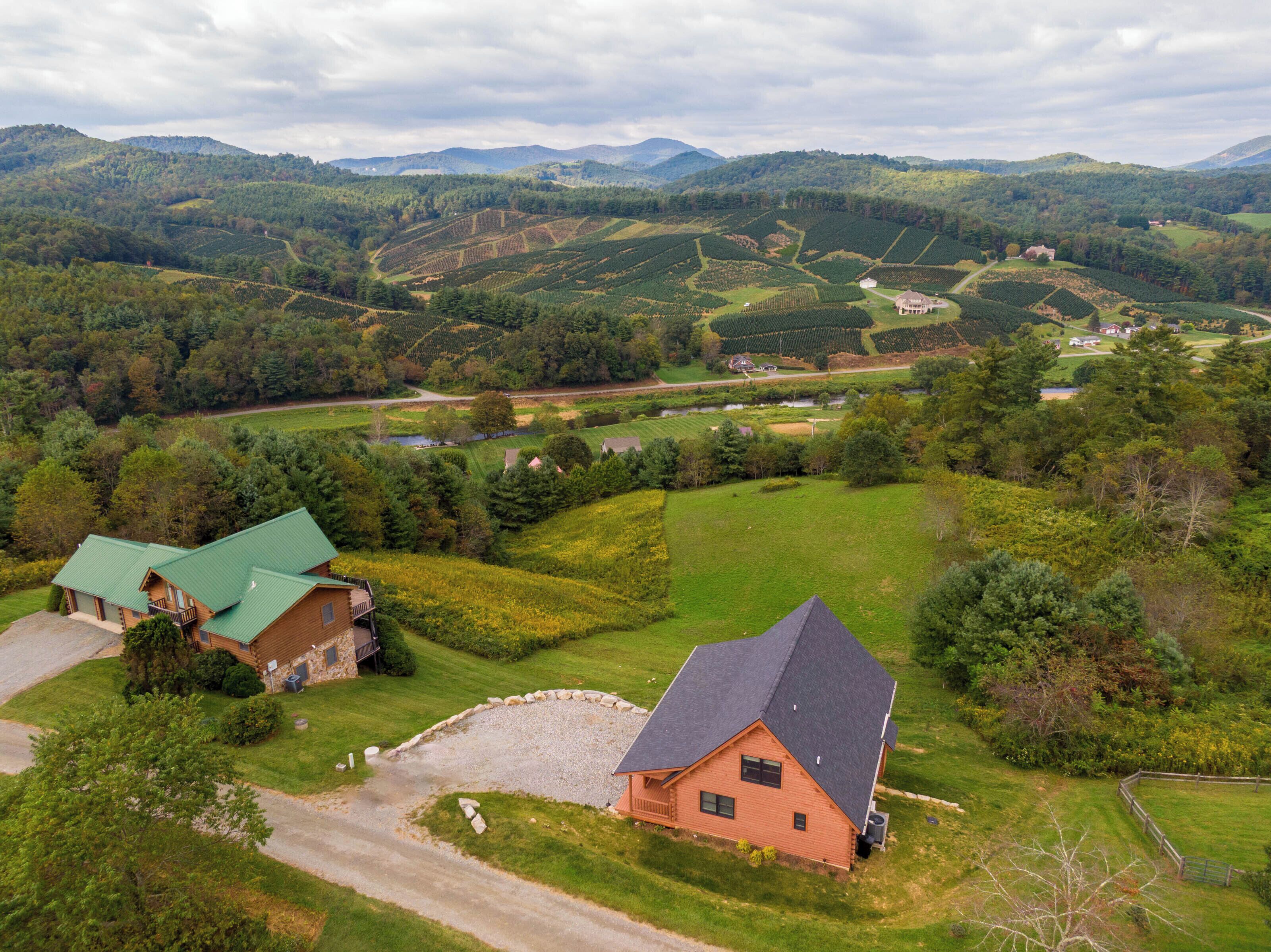 A rural landscape with a large house, a smaller cabin, and a river.
