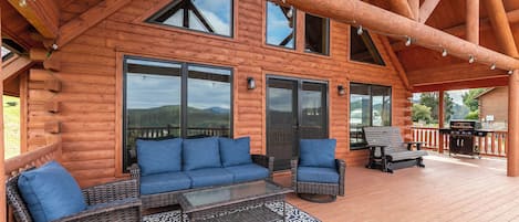 A wooden cabin with a covered deck, large windows, and outdoor seating.