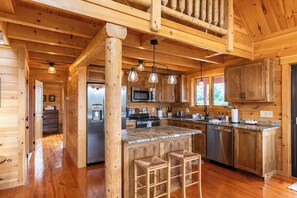 Interior de una cabaña de madera con cocina, pisos de madera y una zona de bar.