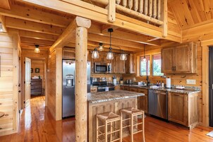 Interior de una cabaña de madera con cocina, pisos de madera y una zona de bar.
