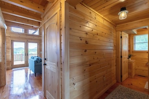 A wooden interior with a sofa, a door, and a window. - Chasing Clouds Cabin (Fleetwood)