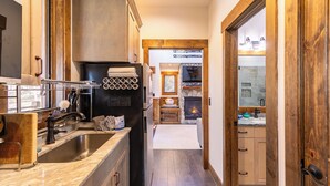 A kitchen with a large sink, a stove, and a refrigerator. There is a wooden door leading to another room. - Ripple Run at Eagles Nest (Banner Elk)