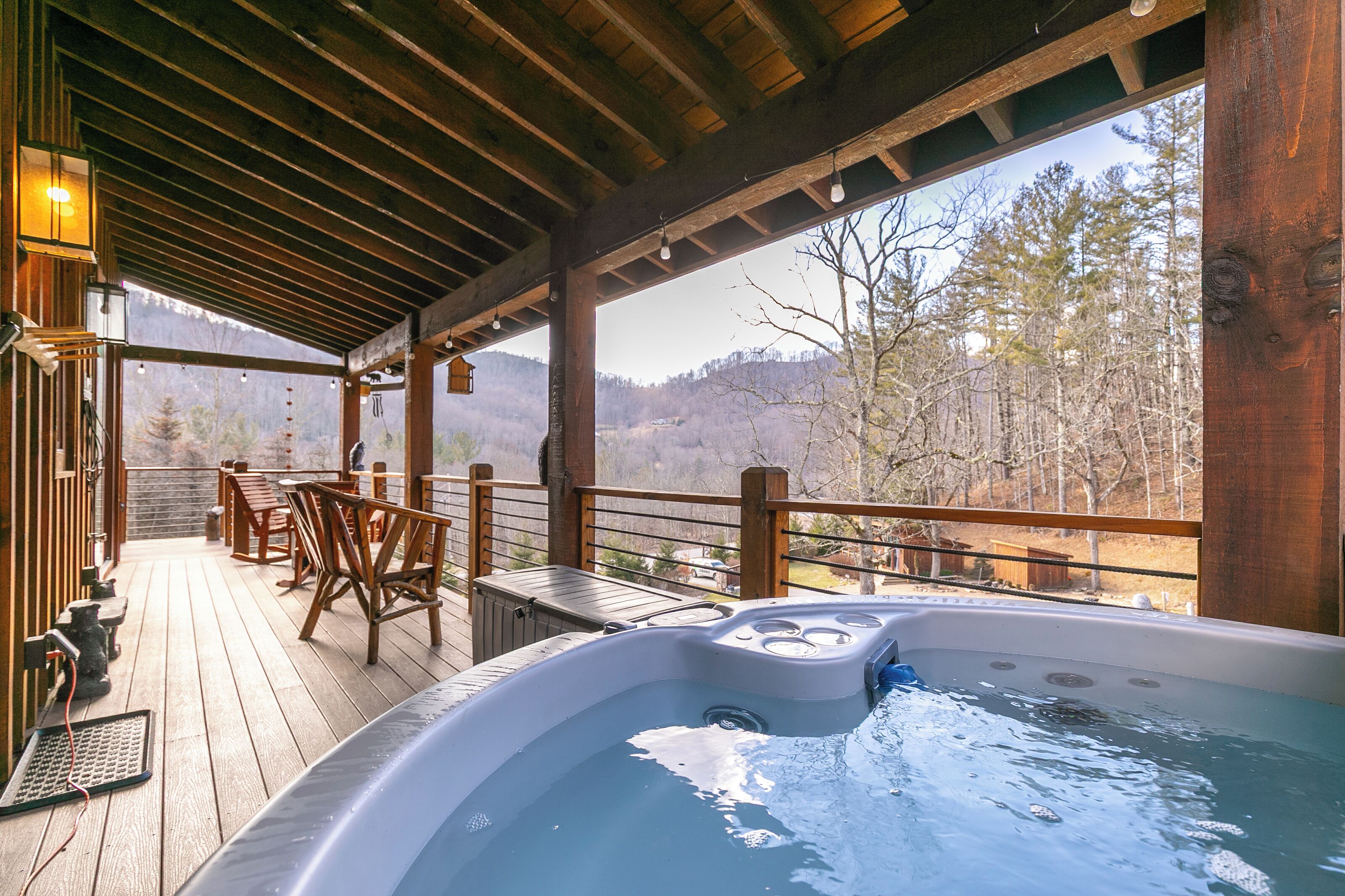 Terraza de madera con mobiliario exterior y jacuzzi.