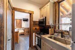 A modern kitchen with wooden cabinets, a stainless steel sink, and a built-in oven. - Ripple Run at Eagles Nest (Banner Elk)