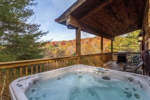 A hot tub on a wooden deck with a view of autumn trees. - River Ridge (Boone)