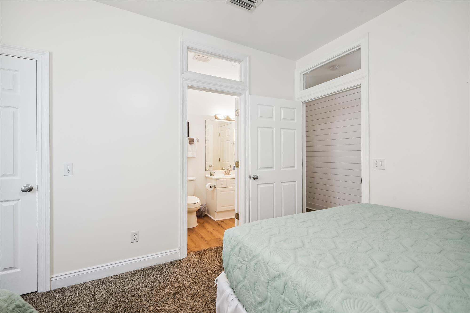 A bedroom with a bed, a door leading to a bathroom, and a closet.