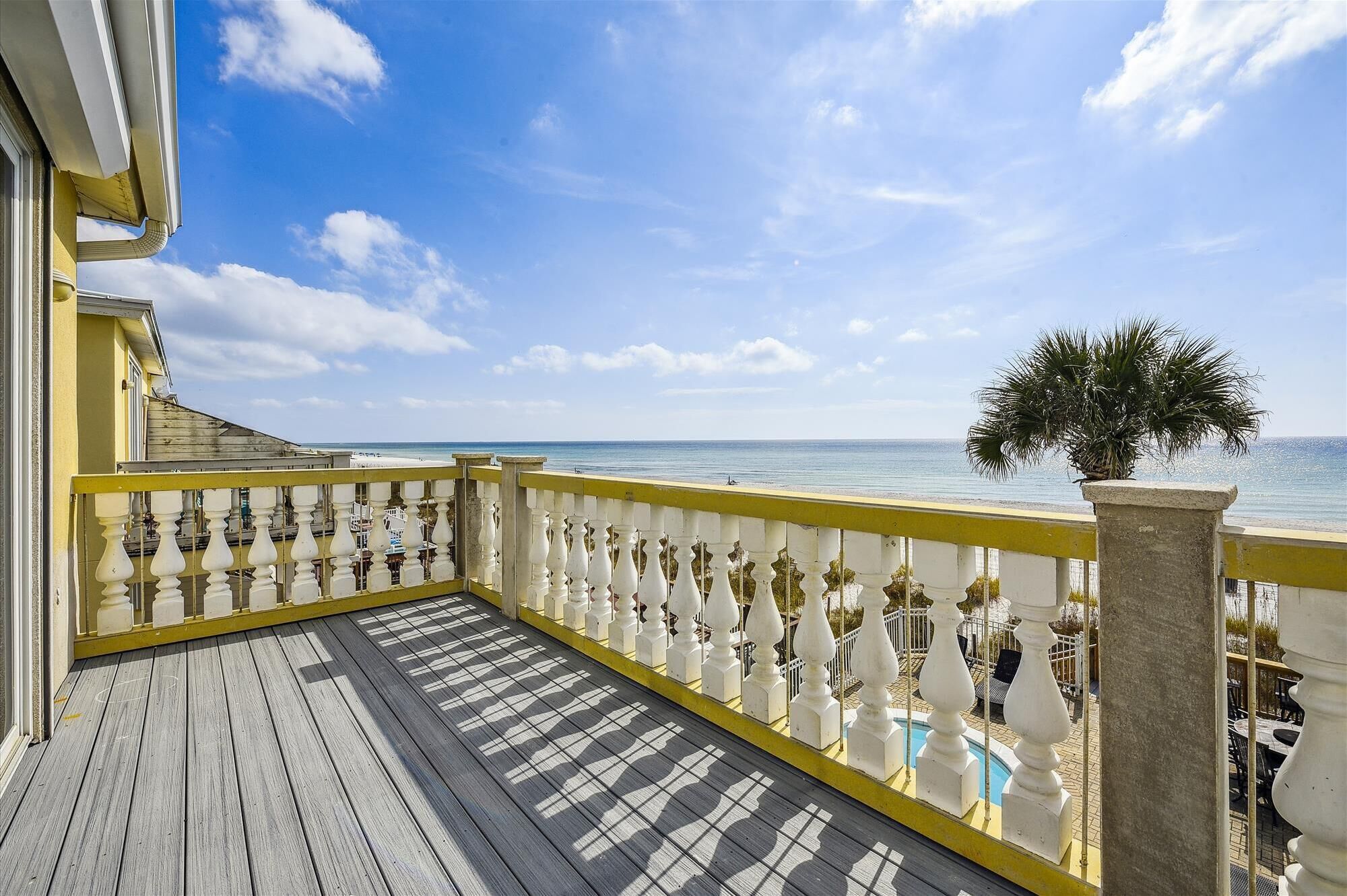 A wooden deck with a white balustrade overlooking a beach.