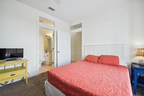 Ein Schlafzimmer mit einem Bett, einem Fernseher auf einem gelben Tisch und einer Lampe auf einem blauen Tisch.