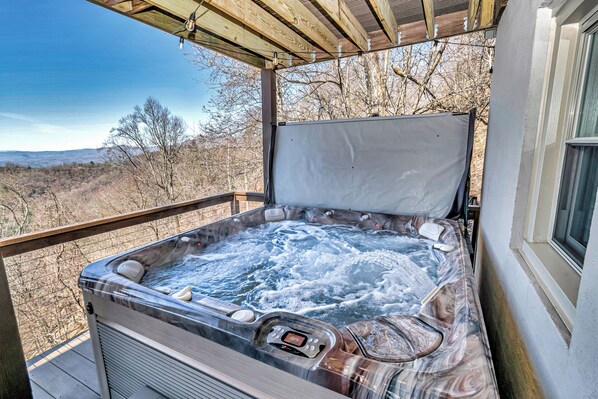 Un bain à remous doté d’un affichage numérique de la température, entouré d’une terrasse en bois et offrant une vue sur un paysage montagneux.