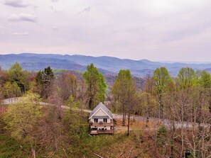 Ein Haus, umgeben von Bäumen und Bergen.