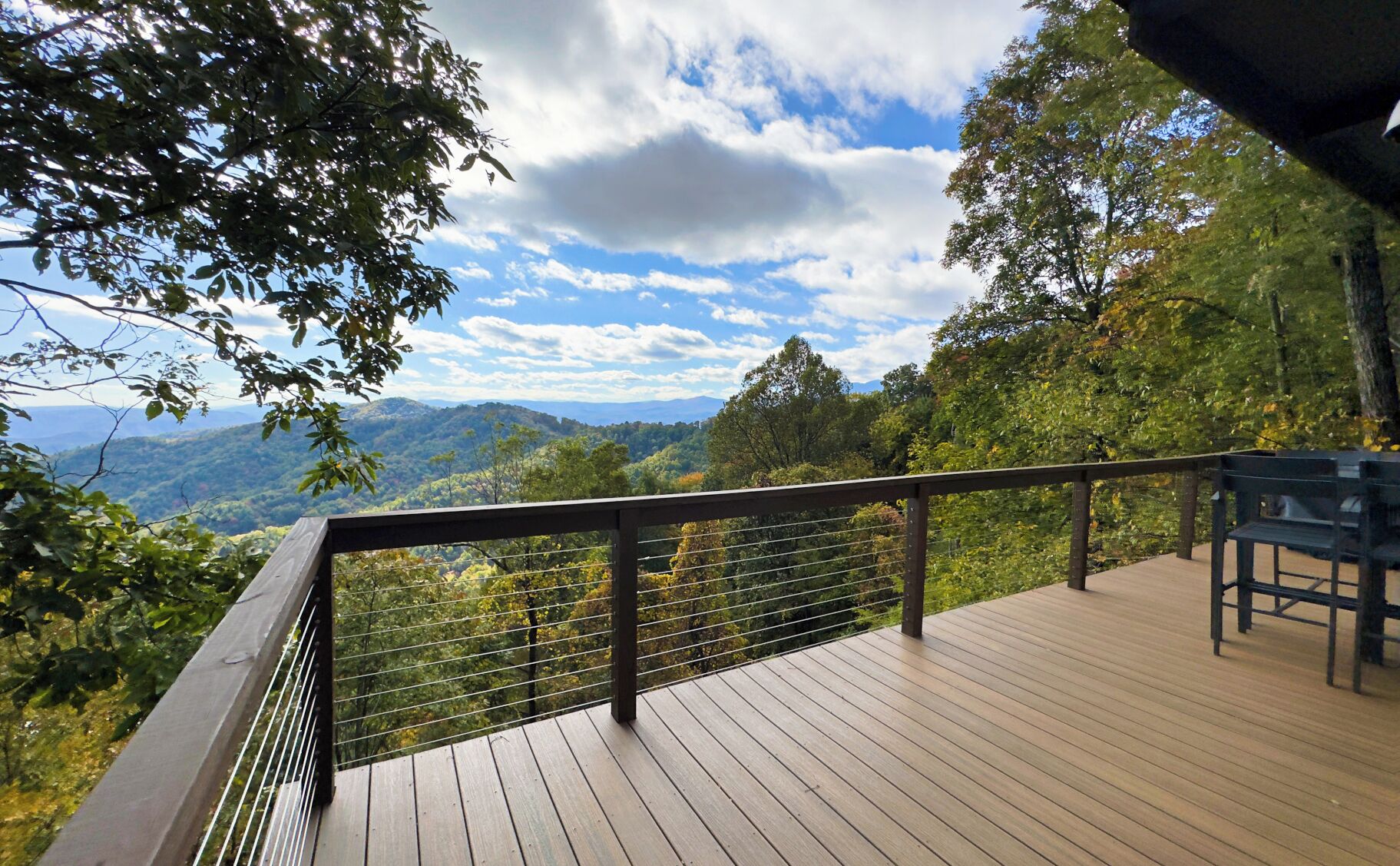 Um deck de madeira com guarda-corpo de metal, com vista para uma paisagem montanhosa.