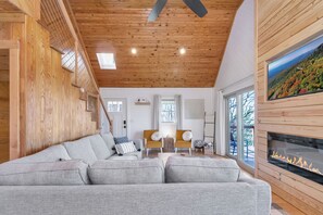 Ein gemütliches Wohnzimmer mit grauem Sofa, Holzboden und Kamin.