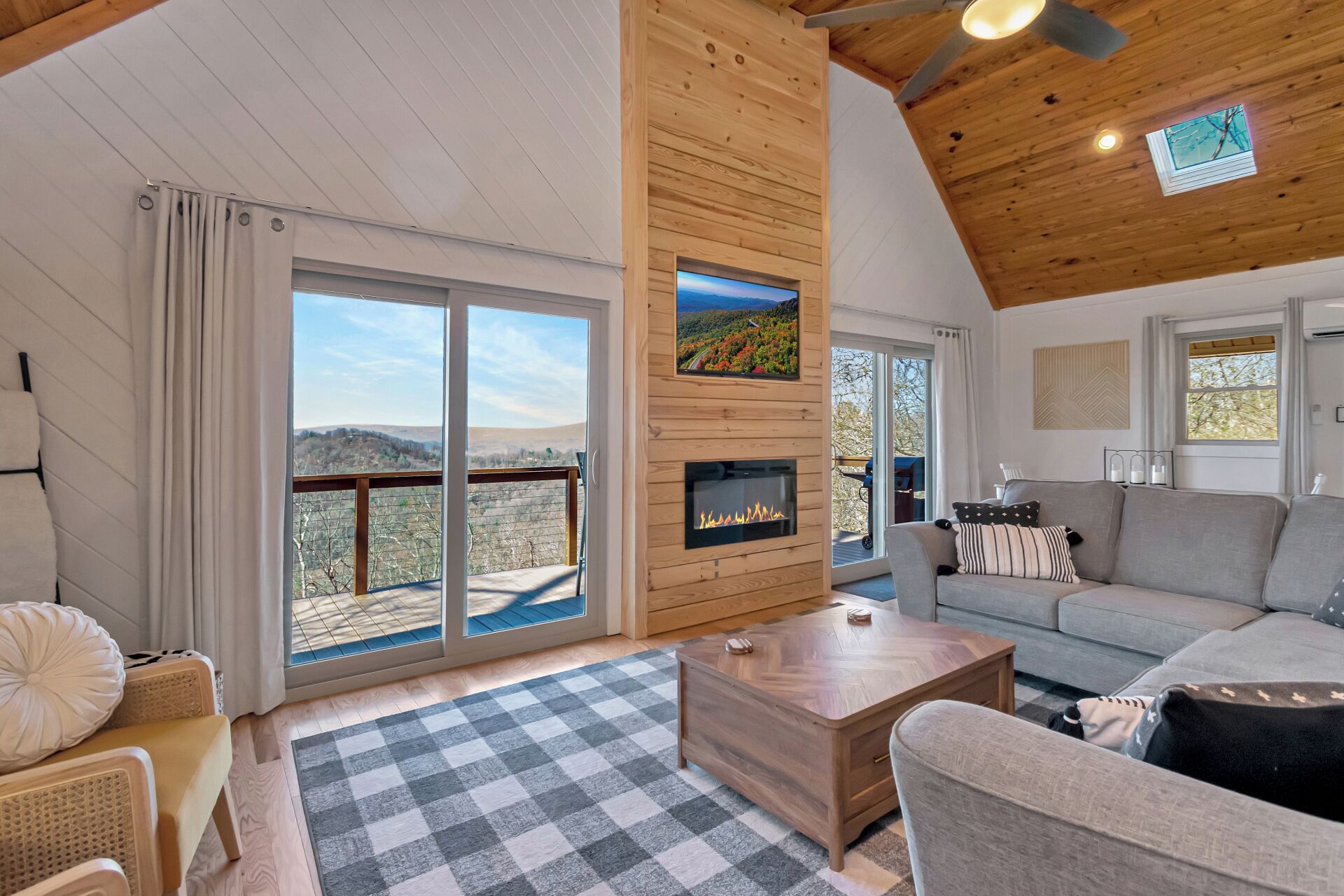 A spacious living area with a fireplace, a sofa, a coffee table, and a large window offering a scenic view.