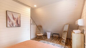 A bedroom with a bed, a hanging chair, a mirror, and a laundry basket. - Calling Me Home (Lenoir)