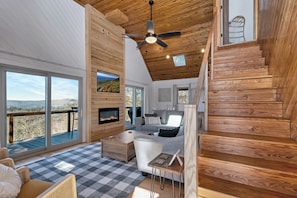 A modern interior with a fireplace, a sofa, and a dining area. - Calling Me Home (Lenoir)