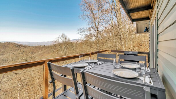 A dining area with a table set for four, overlooking a scenic landscape. - Calling Me Home (Lenoir)