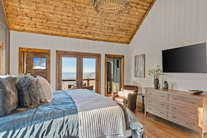 Ein Schlafzimmer mit einem großen Bett, Holzboden, einem Fernseher und Blick aus dem Fenster.