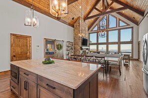 A spacious kitchen with a large island, wooden beams, and a view through large windows. - Altitude Adjustment at Eagles Nest (Elk Park)