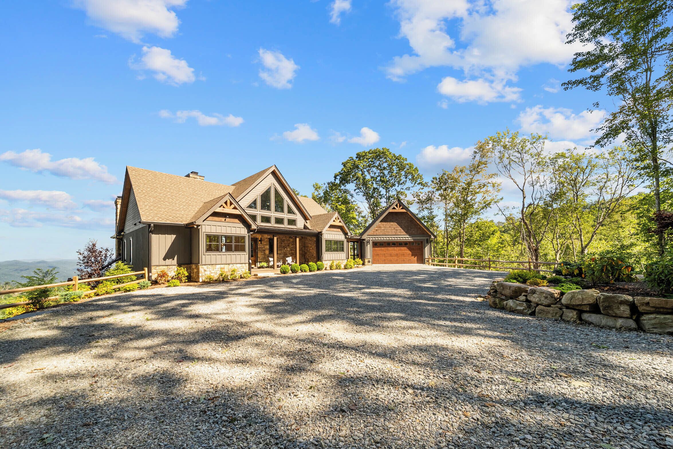 A two-story house with a gravel driveway and stone walls.