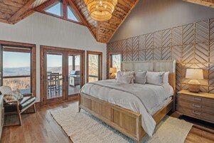 Un dormitorio con una cama grande, cabecera de madera y vistas a través de puertas de cristal.