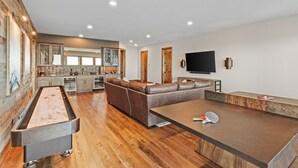 A modern living room with a pool table, a large sectional sofa, and a flat-screen TV mounted on the wall. - Altitude Adjustment at Eagles Nest (Elk Park)