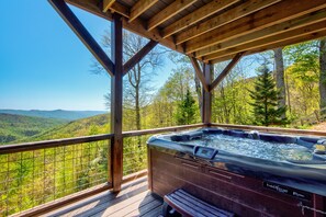 Un jacuzzi en una terraza de madera con vistas a un valle boscoso.