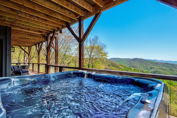 Un jacuzzi bajo una pérgola de madera con vistas a montañas.
