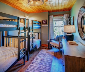 A cozy room with bunk beds, a desk, a chair, and a lamp.