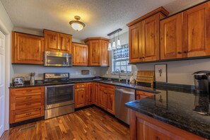 A kitchen with wooden cabinets, stainless steel appliances, and a black granite countertop. - Petes Alpine Retreat (Banner Elk)