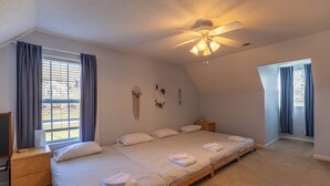 A bedroom with a large bed, a ceiling fan, and a window with curtains. - Petes Alpine Retreat (Banner Elk)