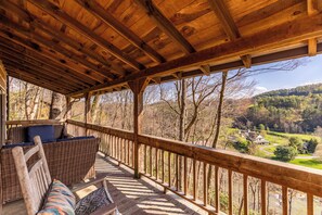 Eine Holzterrasse mit Korbmöbeln und Blick auf ein Tal.