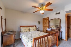 A bedroom with a wooden bed, a ceiling fan, a dresser, a mirror, and a door. - Daniel Boone Lodge (Boone)