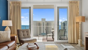 A hotel room with a balcony, a sofa, a chair, a table, and a lamp. - Laketown Wharf 809 (Panama City Beach)