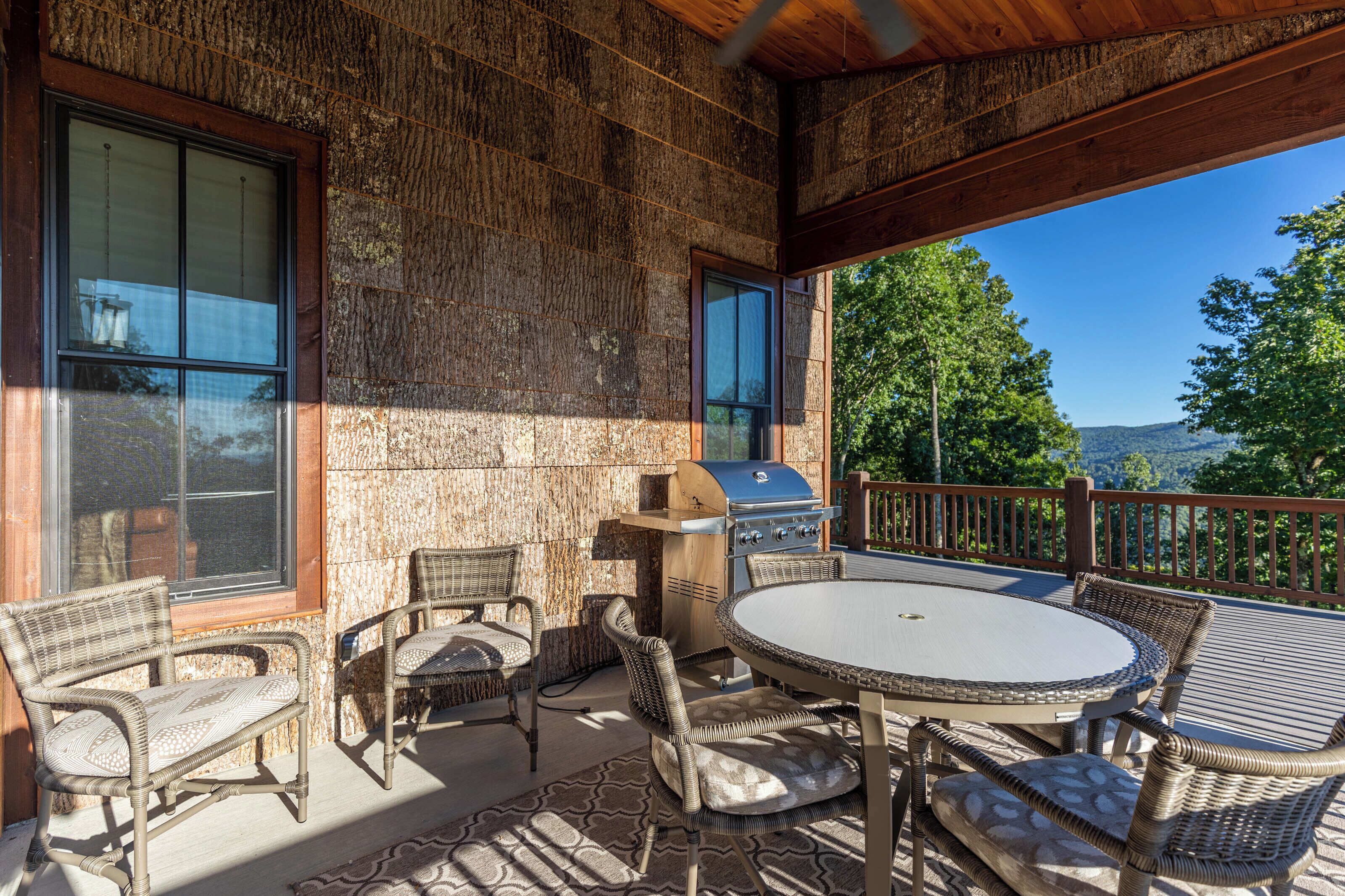 Une terrasse extérieure aménagée avec des meubles en osier, un barbecue et une vue sur les montagnes.