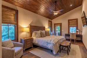 A bedroom with a large bed, wooden ceiling, and a desk with a chair. - One Sweet Getaway at Eagles Nest (Banner Elk)