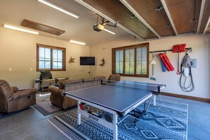 A living room with a ping pong table, two sofas, a TV, and a projector mounted on the ceiling. - One Sweet Getaway at Eagles Nest (Banner Elk)