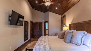 Un dormitorio con una cama grande, techo de madera y ventilador de techo.